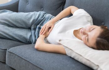 Sick asian young woman in pain, hand holding belly, stomach pain from food poisoning, girl hurt abdomen ache and digestive problem, gastritis or diarrhea. Health care inflammation, abdominal problem